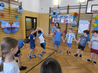 Dzieci trzymając się za ręce próbują przekazać hula-hop kolejnej osobie bez puszczenia rąk