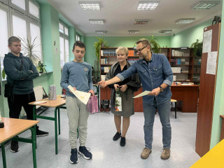 Pan dyrektor wręcza dyplom i gratuluje uczniowi.