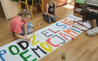 Uczniowie malują farbami napis podziel się emocjami.