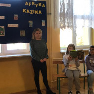 Osoby czytające książkę pt. "Afryka Kazika" - Pani bibliotekarka Katarzyna Komorowska i uczennice z klasy IV B: Amelia i Natalia