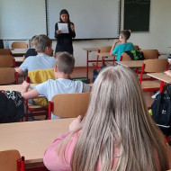 Uczniowie klas V i VI w sali piszą dyktando czytane przez nauczycielkę.