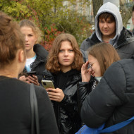 Uczniowie z kl. 8b na Placu Wolności wykonują zadania na telefonie podczas gry miejskiej.