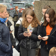 Uczniowie z kl. 8c wraz z wychowawcą na Placu Wolności wykonują zadania na telefonie podczas gry miejskiej.