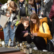 Uczennice rozwiązują zadanie na telefonie na Cmentarzu Starym przy grobie Stefana Artwińskiego.