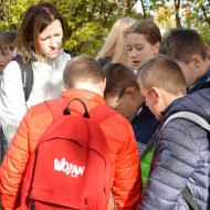 Uczniowie rozwiązują zadanie na telefonie na Cmentarzu Starym.