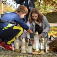 Uczeń i uczennica zapalają znicz przy grobie Stefana Artwińskiego na Cmentarzu Starym.