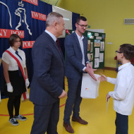 Dyrektor szkoły Mirosław Gęborek i prezes Stowarzyszenia im Stefana Artwińskiego wręczają uczniowi nagrodę.