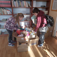 Uczennice segregują dary w bibliotece.