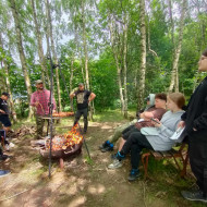 Uczniowie smażą kiełbaski i słuchają o rodzajach ognisk.