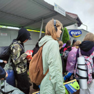 Uczniowie stoją na przystanku autobusowym.