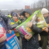 Uczniowie niosący worki z karmą dla zwierząt do schroniska.