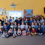 Grupa przedszkolna ubrana w niebieskie koszulki pozuje do zdjęcia.