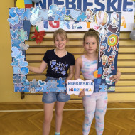 Uczennice pozują do zdjęcia na tle fotobudki i napisem NIEBIESKIE IGRZYSKA.