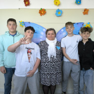 Uczniowie klasy 8b razem z wychowawczynią panią Kasią Knap pozują do zdjęcia na tle motyla.