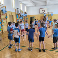 Dzieci trzymając się za ręce próbują przekazać hula-hop kolejnej osobie bez puszczenia rąk