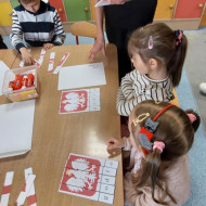 Dzieci układają puzzle przy asyście ósmoklasisty.