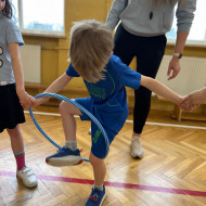 Chłopiec trzymając się za ręce próbuje przekazać hula-hop kolejnej osobie bez puszczenia rąk