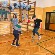 Chłopiec ciągnie przywiązany sznurek do hula-hop a drugi w tym czasie próbuje do niego skakać do przodu i tyłu