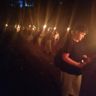 Uczniowie nocą spacerują z pochodniami.