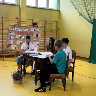Czworo uczniów siedzi przy dębowym stole i czyta wiersze Jana Kochanowskiego.