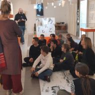 Uczniowie siedzą na podłodze i słuchają opowieści o Edmundzie Niziurskim.