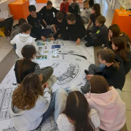 Uczniowie siedzą na podłodze i układają historyjkę obrazkową.