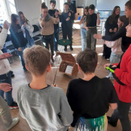 Uczniowie przy pomocy tarczy współpracy otwierają wiklinowy kosz.