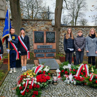 Uczniowie reprezentujący szkołę na obchodach rocznicy śmierci patrona stoją przy jego grobie.