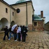 Uczniowie na dziedzińcu klasztoru Franciszkanów rozwiązują zadania z gry miejskiej.