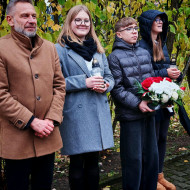 Dyrektor szkoły wraz z delegacją uczniów oczekują na złożenie kwiatów na grobie patrona.