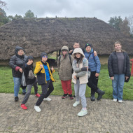 Uczniowie przed chatą pokrytą strzechą.