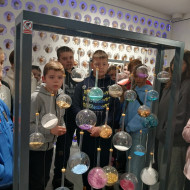 Uczniowie przypatrują się jednej z wystaw muzeum przedstawiającej materiały służące ozdabianiu bombek.