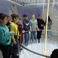 Dzieci oglądają iluminacje świetlne we wnętrzu bombki. 