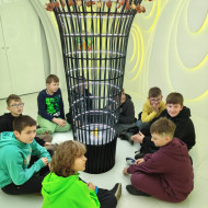 Dzieci oglądają iluminacje świetlne we wnętrzu bombki. 