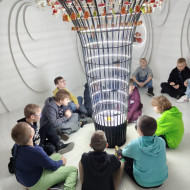 Dzieci oglądają iluminacje świetlne we wnętrzu bombki. 