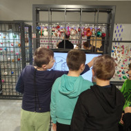 Grupa osób spaceruje między wystawami w muzeum Żywej Bombki.