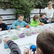 Dzieci dekorują bombki różnymi kolorami farb.