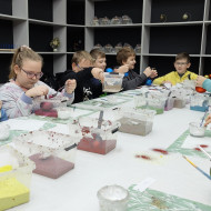 Dzieci dekorują bombki różnymi kolorami farb.