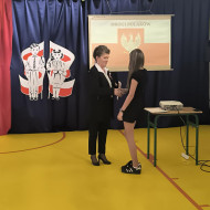 Wicedyrektor wręcza dyplom uczennicy za zajęcie I miejsca w konkursie historycznym.