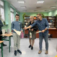 Pan dyrektor wręcza dyplom i gratuluje uczniowi.