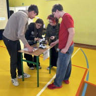 kilku uczniów stoi przy stoliku