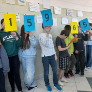 uczniowie stoją na korytarzu trzymając kolorowe kartki