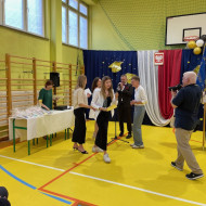 Sala gimnastyczna w szkole, szczęśliwa absolwentka odbiera nagrodę
