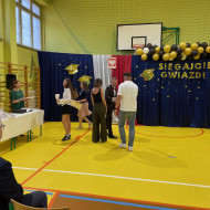 Sala gimnastyczna w szkole, dyrektor gratuluje rodzicom