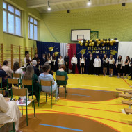 Sala gimnastyczna w szkole, absolwenci przekazują podziękowania dla pracowników szkoły
