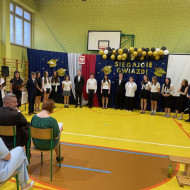 Sala gimnastyczna w szkole, absolwenci przekazują podziękowania dla pracowników szkoły