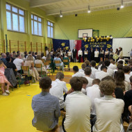 Sala gimnastyczna w szkole, absolwenci przekazują podziękowania dla pracowników szkoły