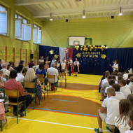 Sala gimnastyczna w szkole, uczeń po odbiorze nagrody okazuje radość