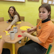 Uczennice przy stoliku w sali lekcyjnej szyją maskotki.