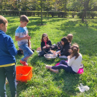 Grupka uczniów na trawniku wykonuje drzewka szczęścia.